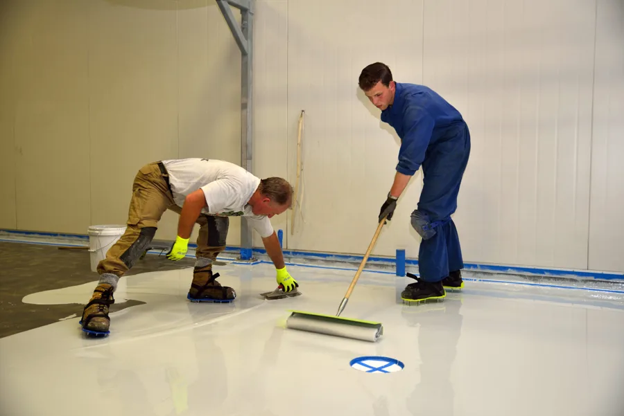 Workers applying a coating to an interior floor